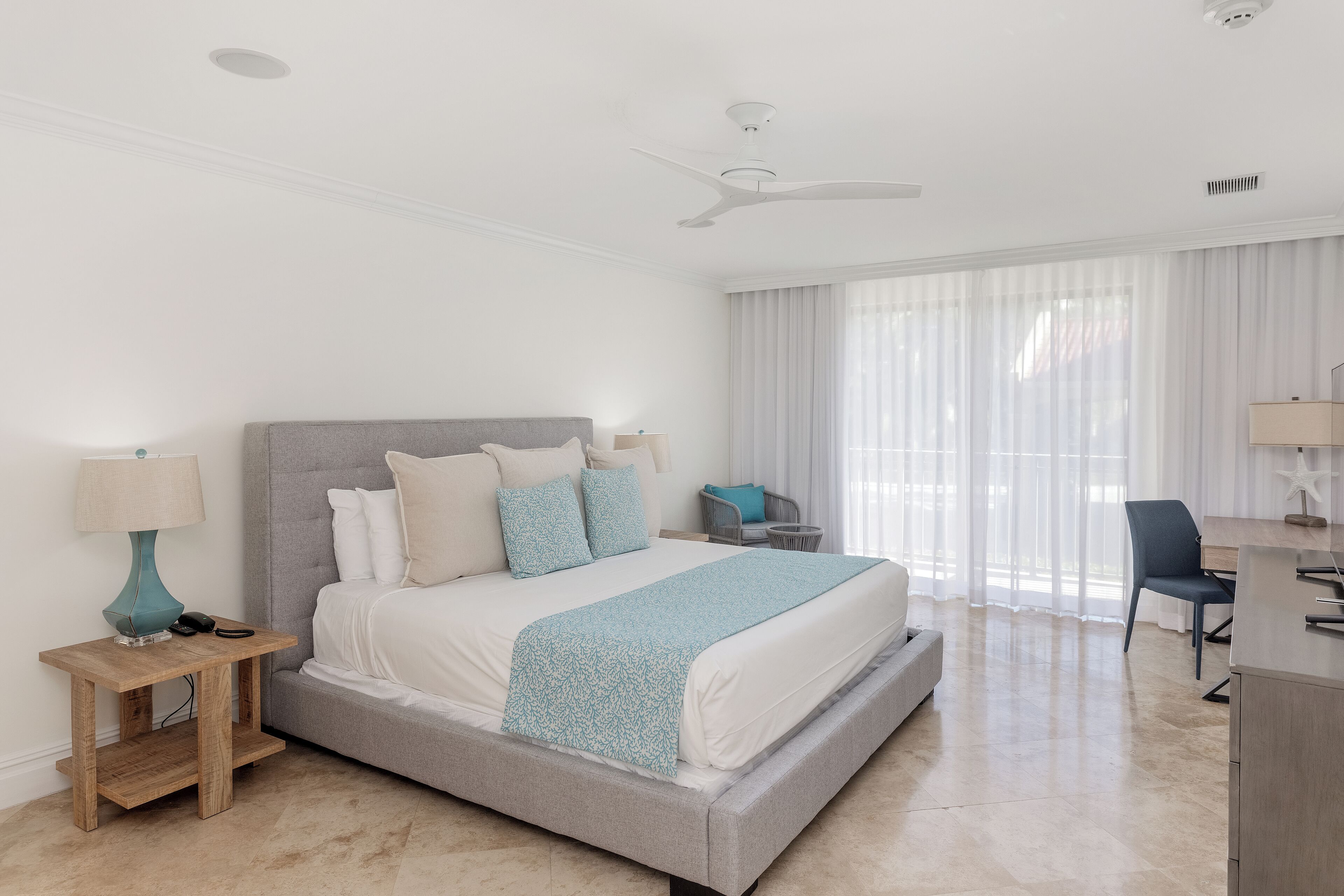 A modern bedroom with a bed, bedside tables, a desk, and a chair.