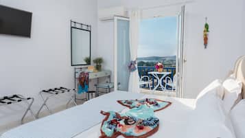 A hotel room with a bed, a desk, a chair, a balcony with a view, and a hanging decoration.