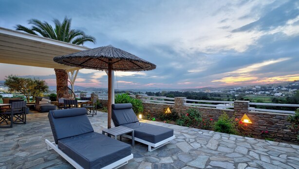 Un patio en la azotea con dos sillones, una mesa y una sombrilla.