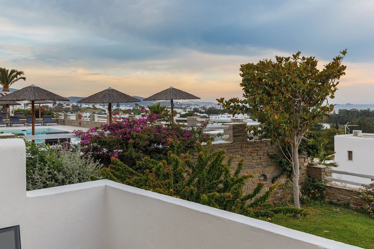A poolside area with umbrellas, a stone wall, and a view of the landscape.