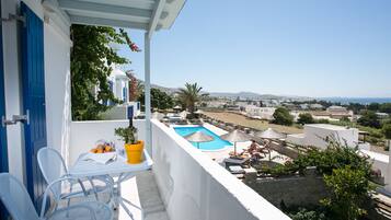 A balcony with a view of a swimming pool and a town in the distance.