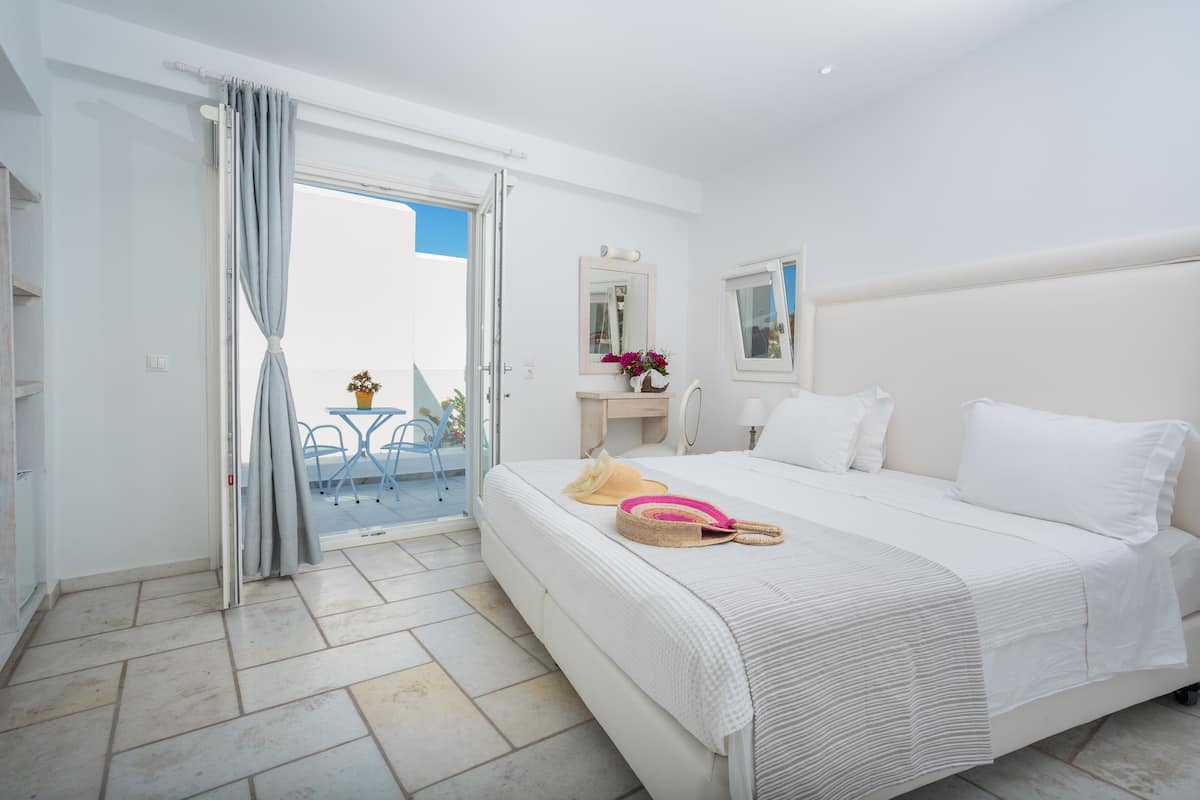 A hotel room with a bed, a bathroom, and a balcony.