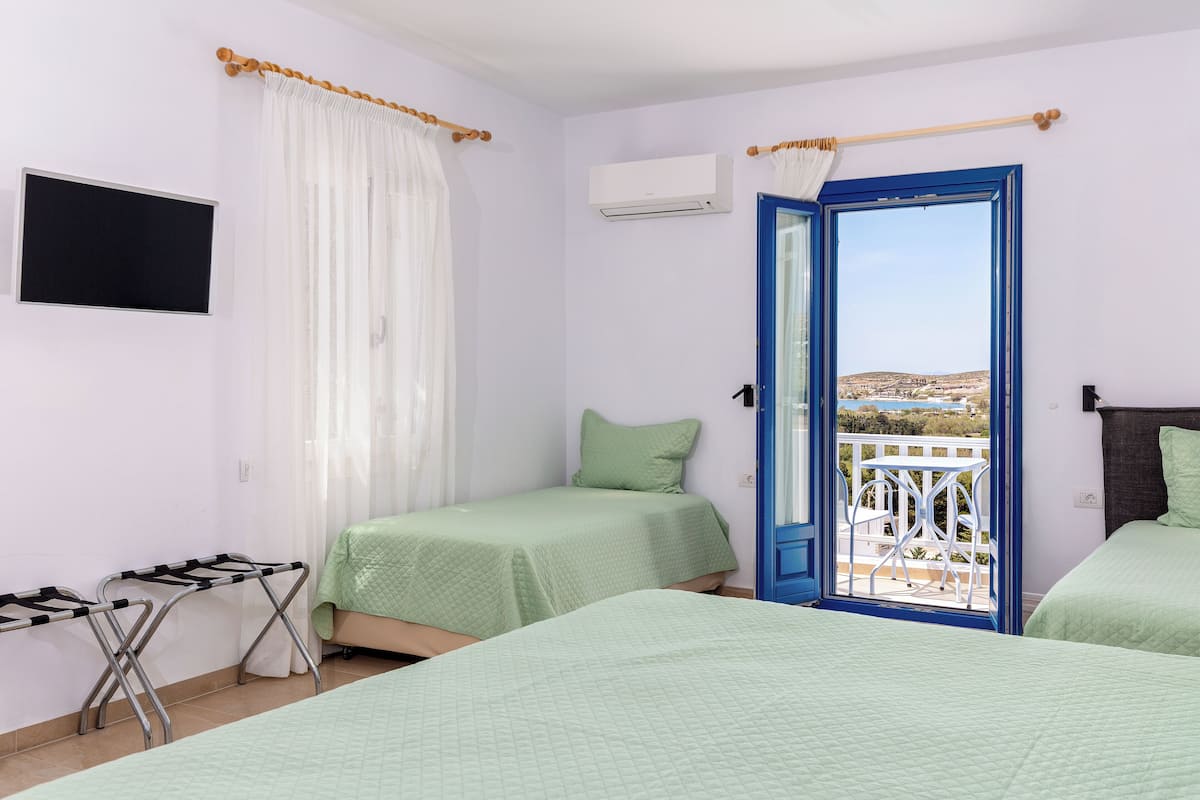 A room with two beds, a TV, an air conditioner, and a balcony with a view.