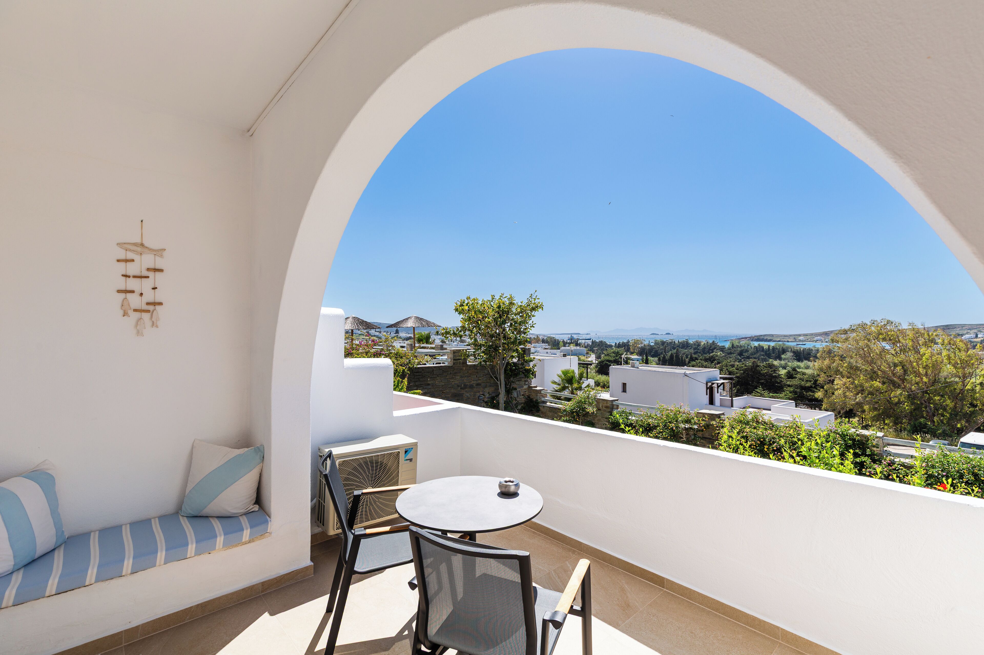 A balcony with a white wall, a round table, and a blue-striped sofa.