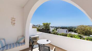 A balcony with a white wall, a round table, and a blue-striped sofa.