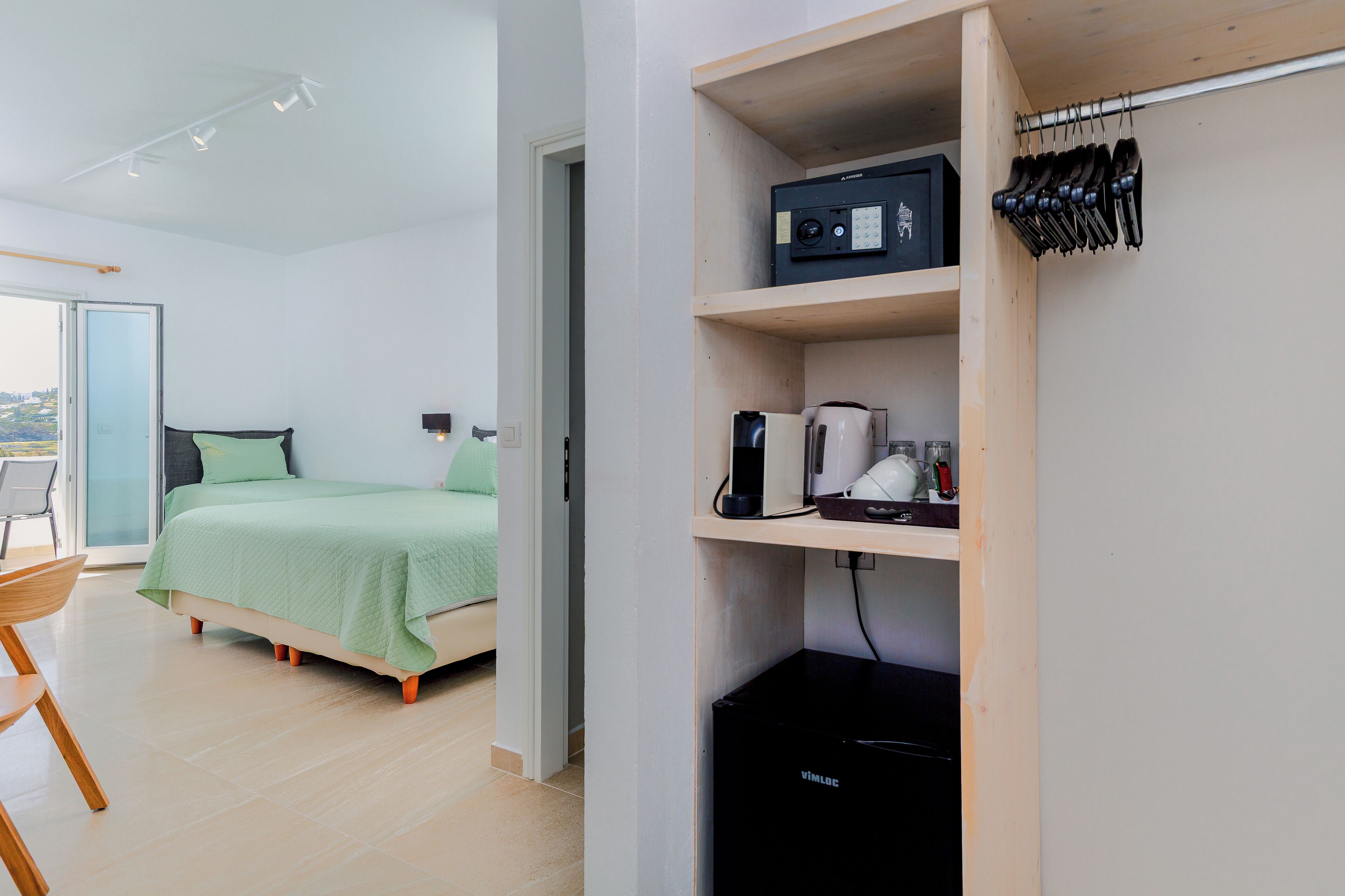 Un dormitorio moderno con cama, un escritorio y una estantería con una cafetera y otros objetos.