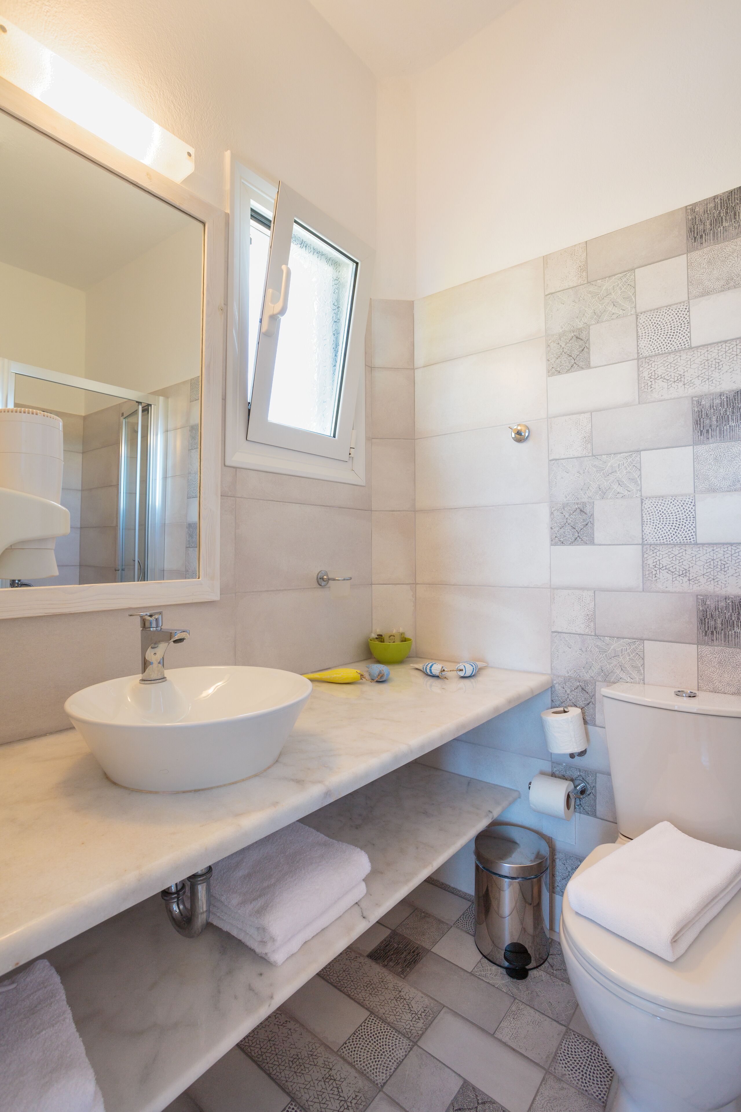 A modern bathroom with a large mirror, a white sink, a toilet, and a shower area.