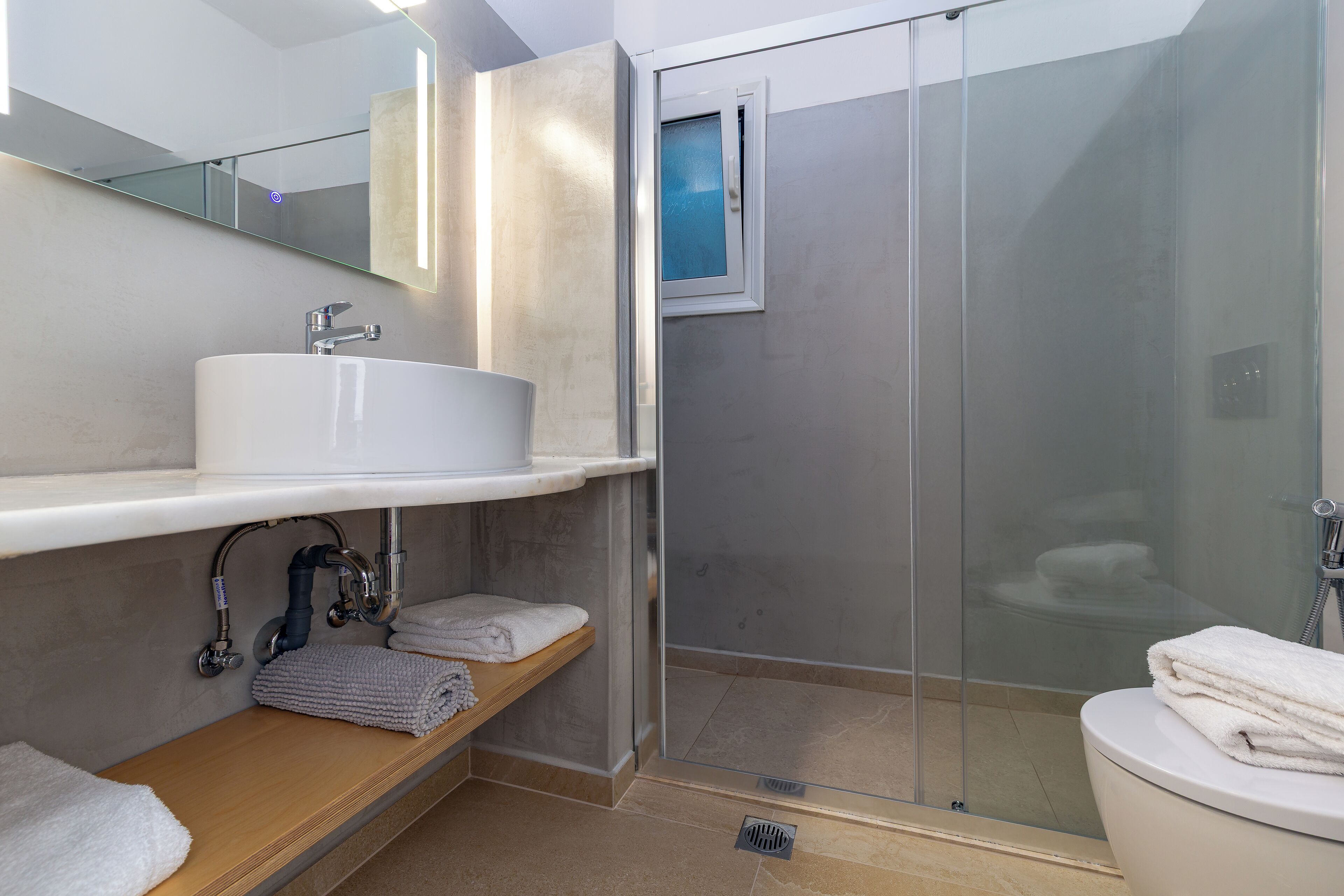 Une salle de bain moderne avec une douche à parois de verre, un lavabo blanc et un miroir au-dessus.