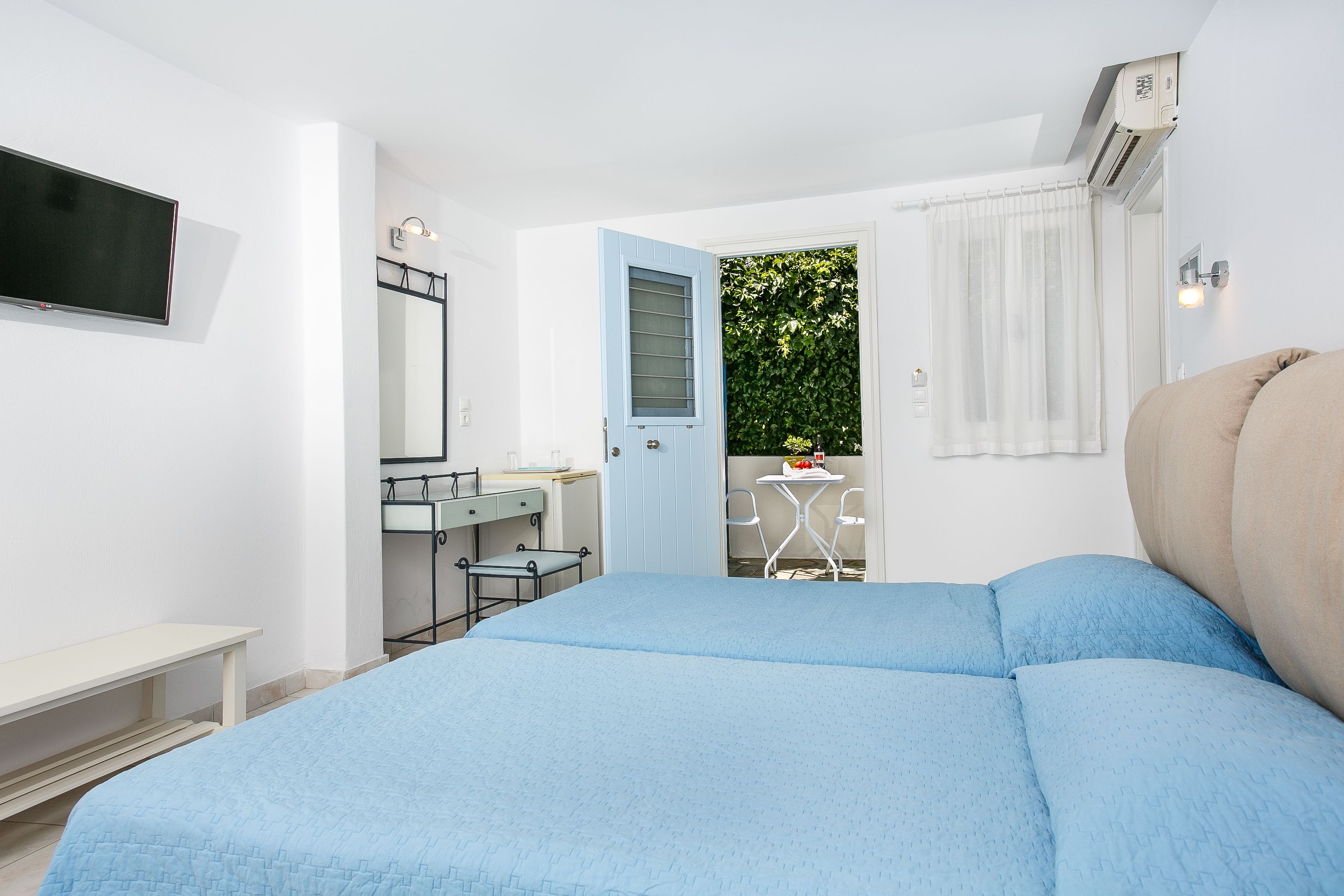 Un dormitorio con cama, escritorio, silla y una pequeña mesa con una planta.