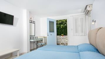 Un dormitorio con cama, escritorio, silla y una pequeña mesa con una planta.