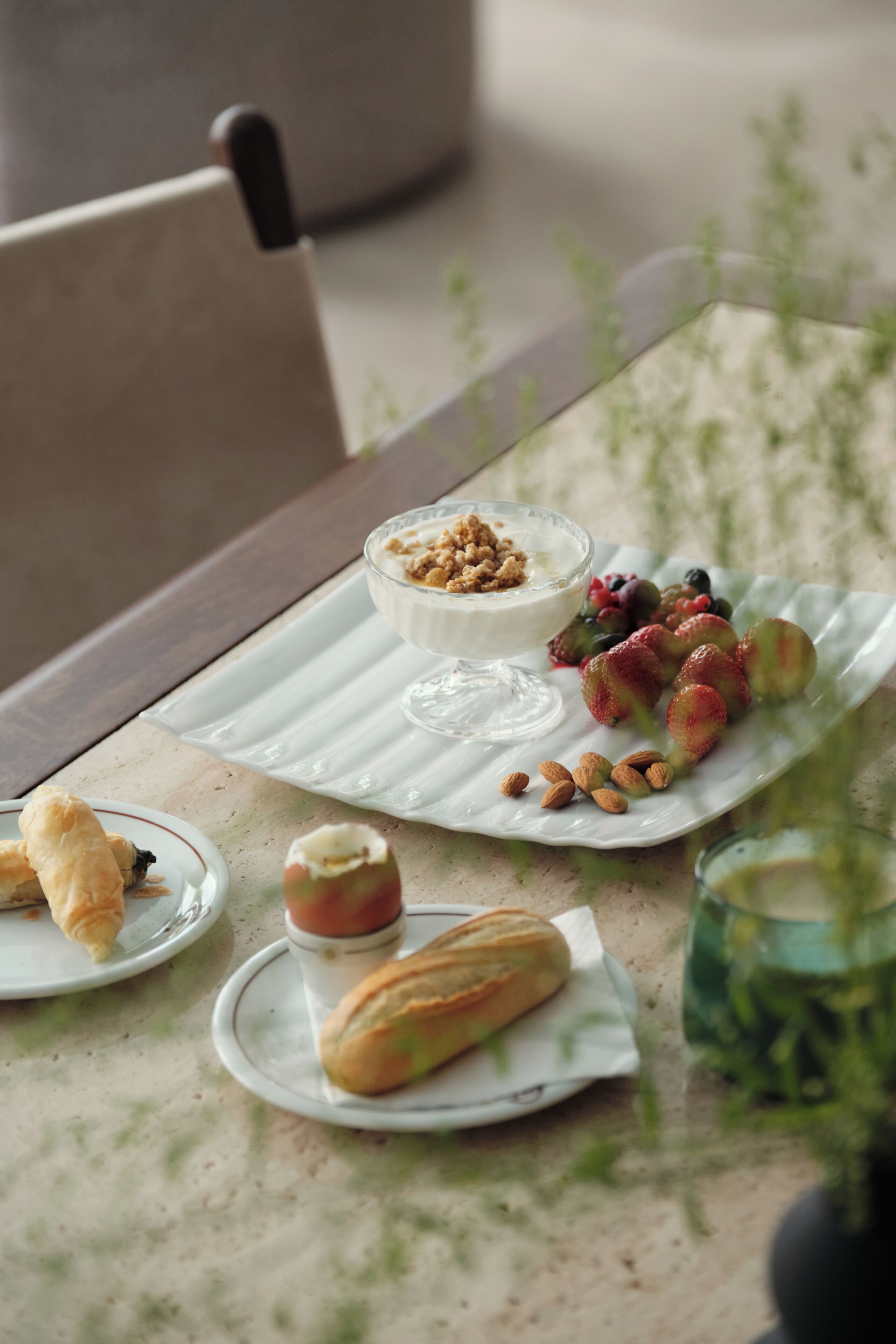 A dining table with a variety of food items including pastries, fruits, and a dessert.