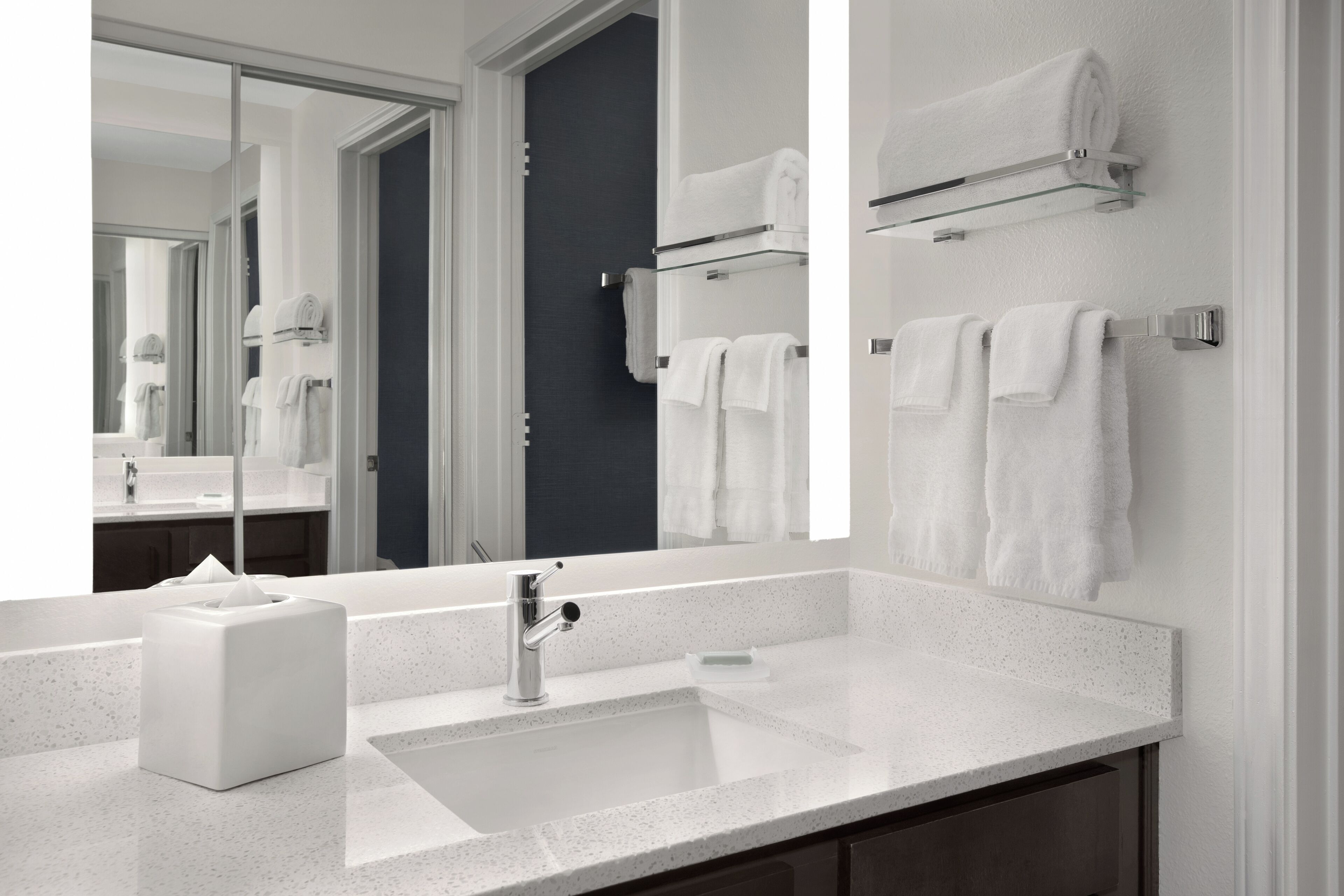 A modern bathroom with a large mirror, a sink, and a towel rack.