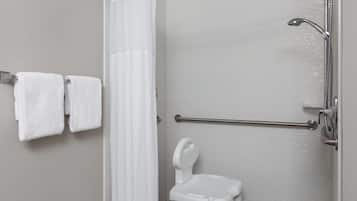 A bathroom with a shower, a grab bar, and a white toilet.
