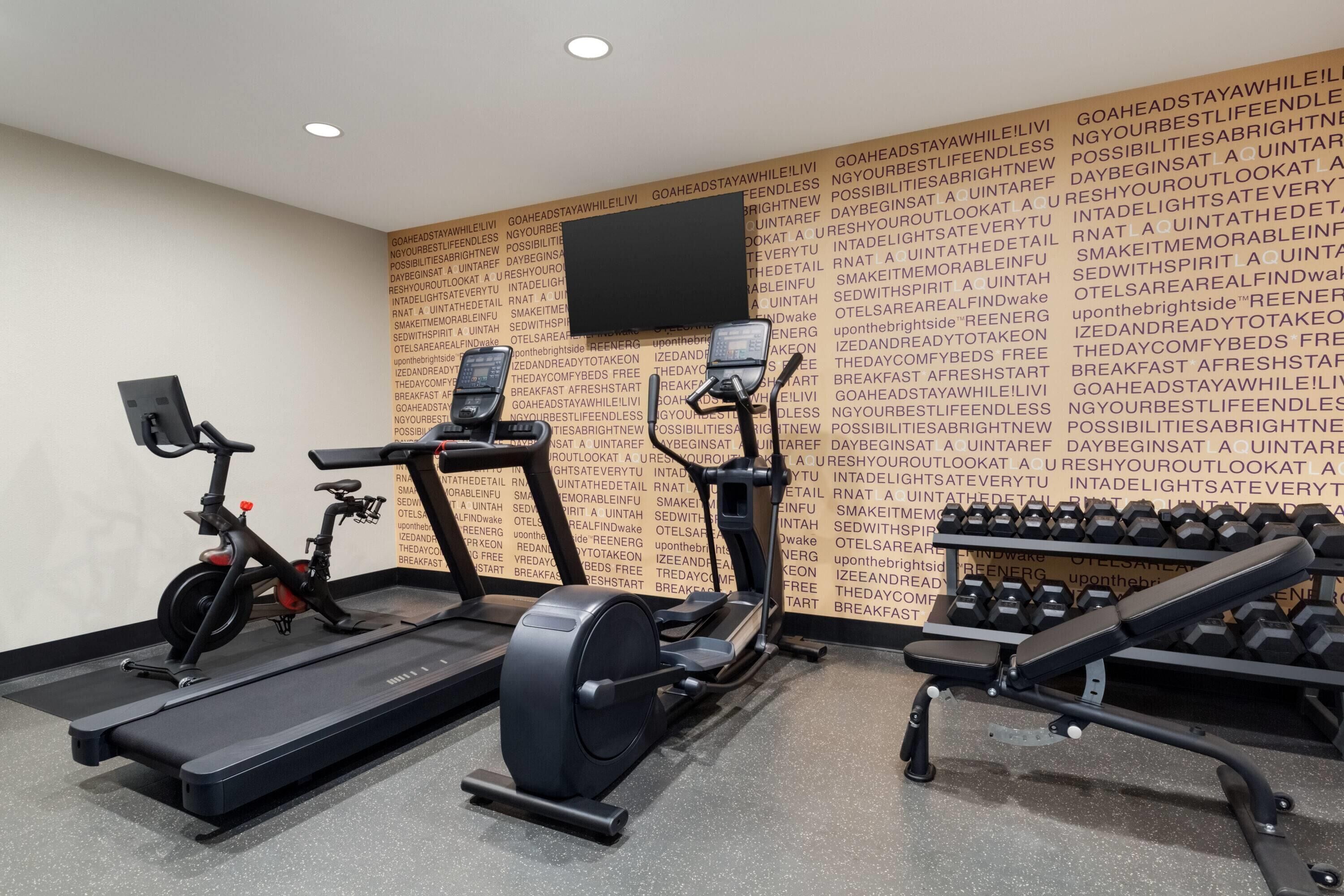 A gym with treadmills, an elliptical, and a bench press area.