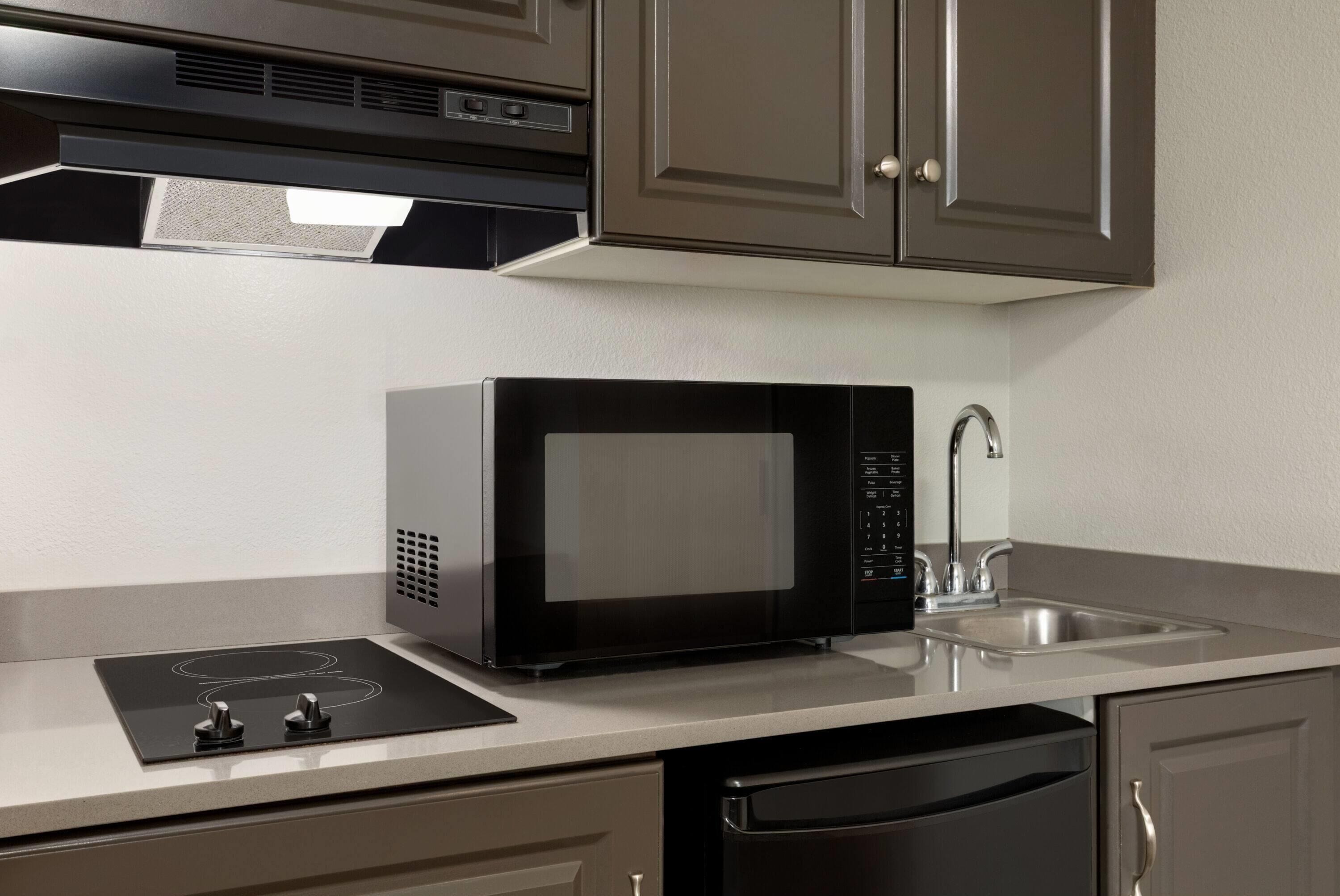 A modern kitchen with a built-in microwave, a sink, and a dishwasher.