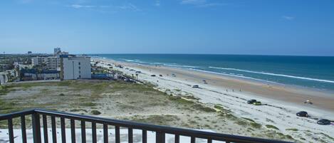 A beach view with a building in the foreground and a clear sky.