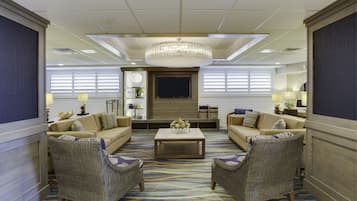 A spacious living area with a large chandelier, two sofas, a coffee table, and a television.