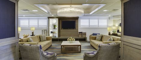 A spacious living area with a large chandelier, two sofas, a coffee table, and a television.