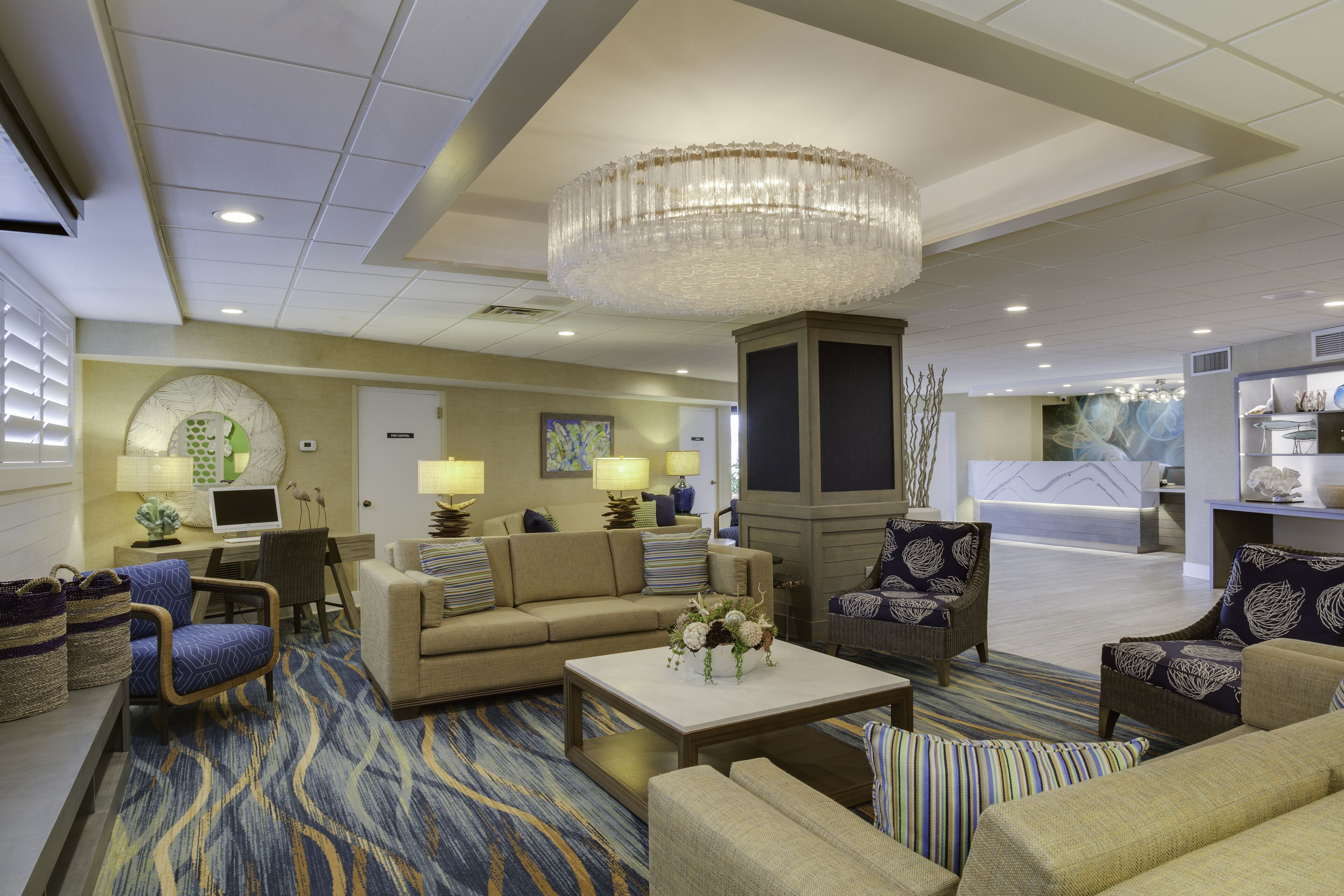 A spacious lobby with a chandelier, sofas, and a reception desk.