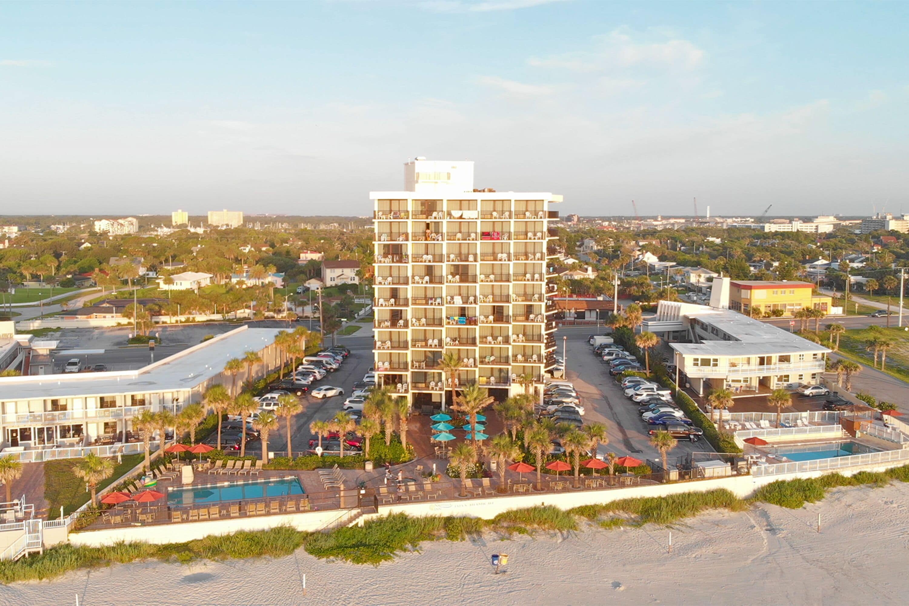 A multi-story hotel with a pool area and beach view.