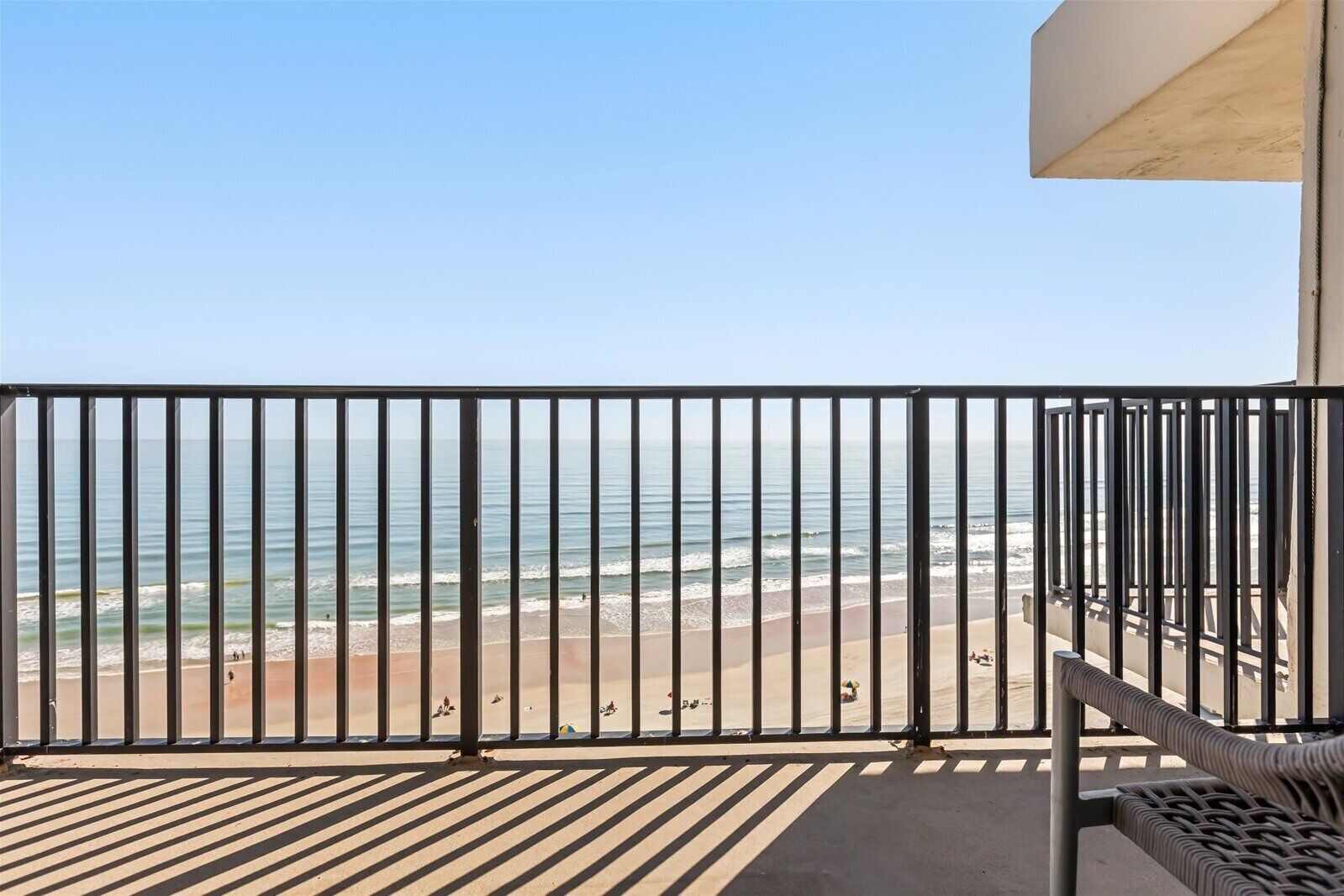 A balcony with a view of the beach and ocean.