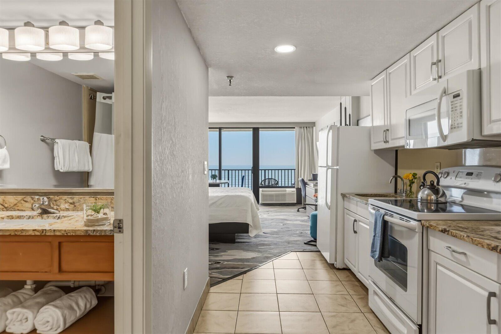Quarto de hotel com cozinha, banheiro e varanda com vista.