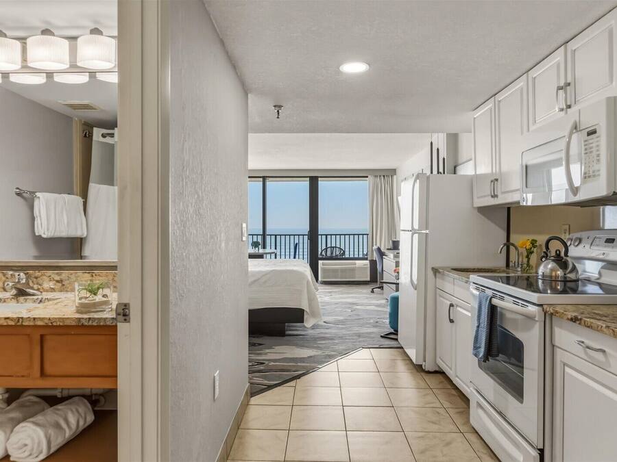 Quarto de hotel com cozinha, banheiro e varanda com vista.