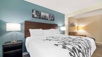 A hotel room with a bed, two bedside tables, a nightstand, and a wall-mounted artwork above the bed.