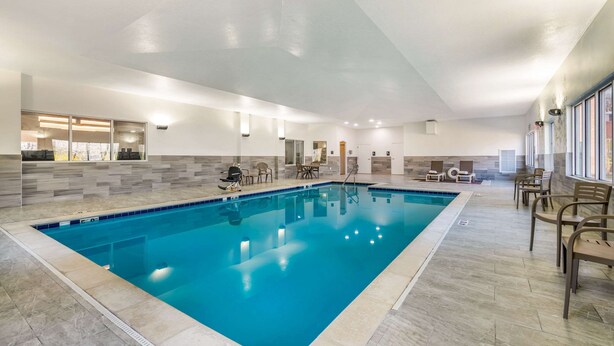 Ein großer, überdachter Pool mit gefliesten Wänden und Boden, umgeben von Liegestühlen und einer Glasscheibe.