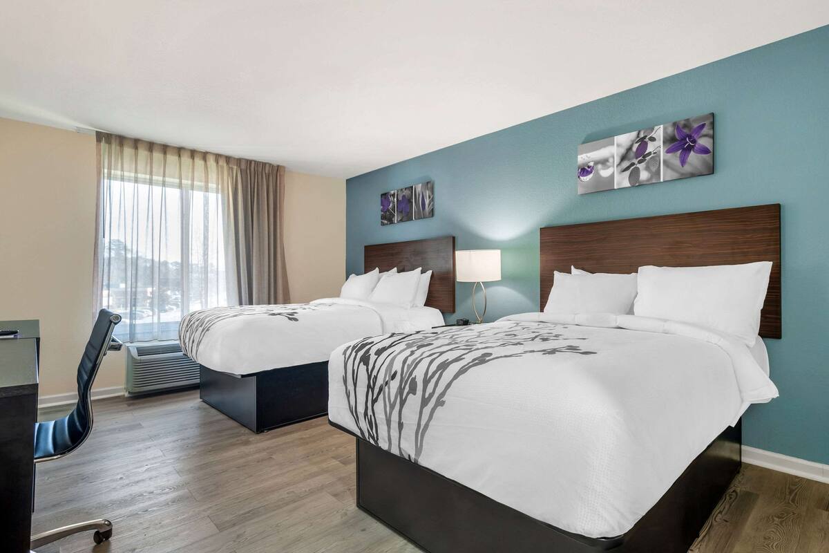 Une chambre d’hôtel avec deux lits, un bureau et une chaise.