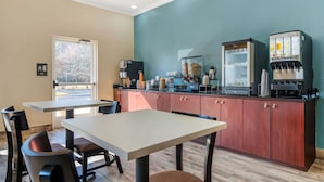 Eine moderne Küche mit einer Kaffeestation, einem Kühlschrank und einem Fenster mit Blick auf Bäume.