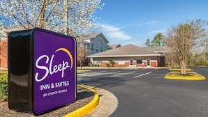 Ein Schild von Sleep Inn & Suites, im Hintergrund ist das Gebäude gut sichtbar.
