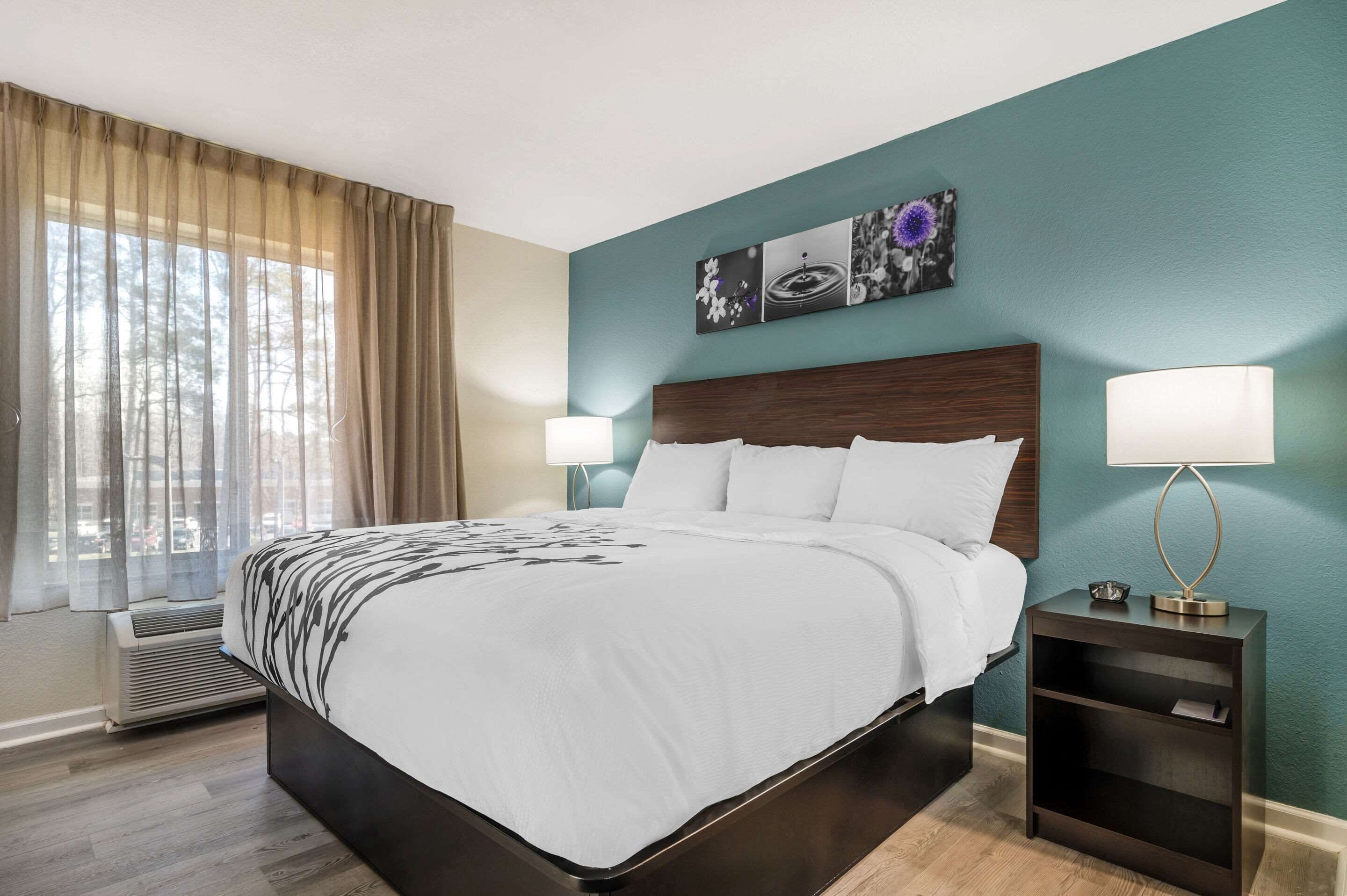 A hotel room with a large bed, two bedside lamps, a nightstand, and a wall-mounted artwork.