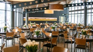 A spacious restaurant with multiple tables and chairs, large windows, and a modern interior design. - Hotel Park Soltau (Soltau)