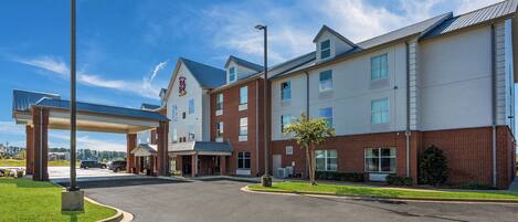A hotel with a covered parking area, a brick facade, and a clear sky.