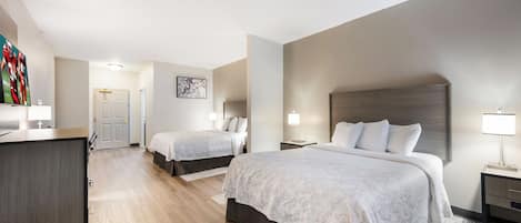A hotel room with two beds, a desk, and a TV.