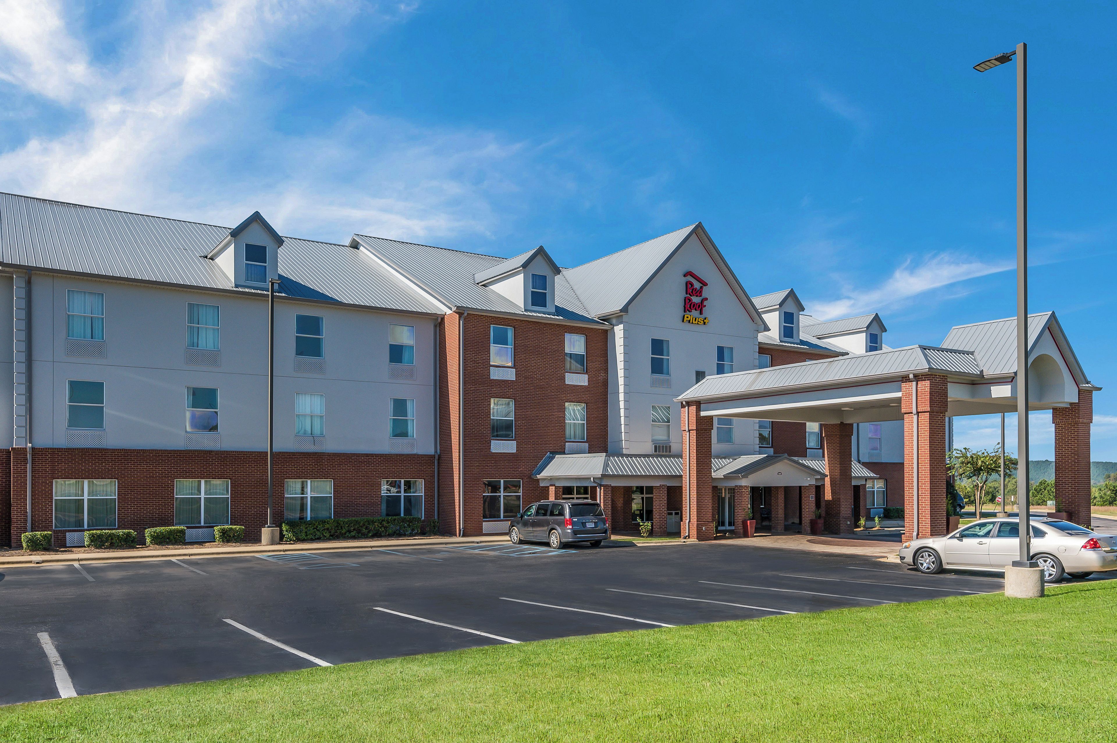 A Red Roof Plus hotel with a parking lot and a covered entrance.