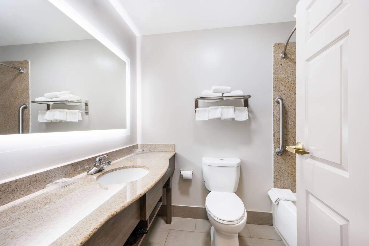 Un baño moderno con lavamanos de granito, inodoro, toallero y cabina de ducha.