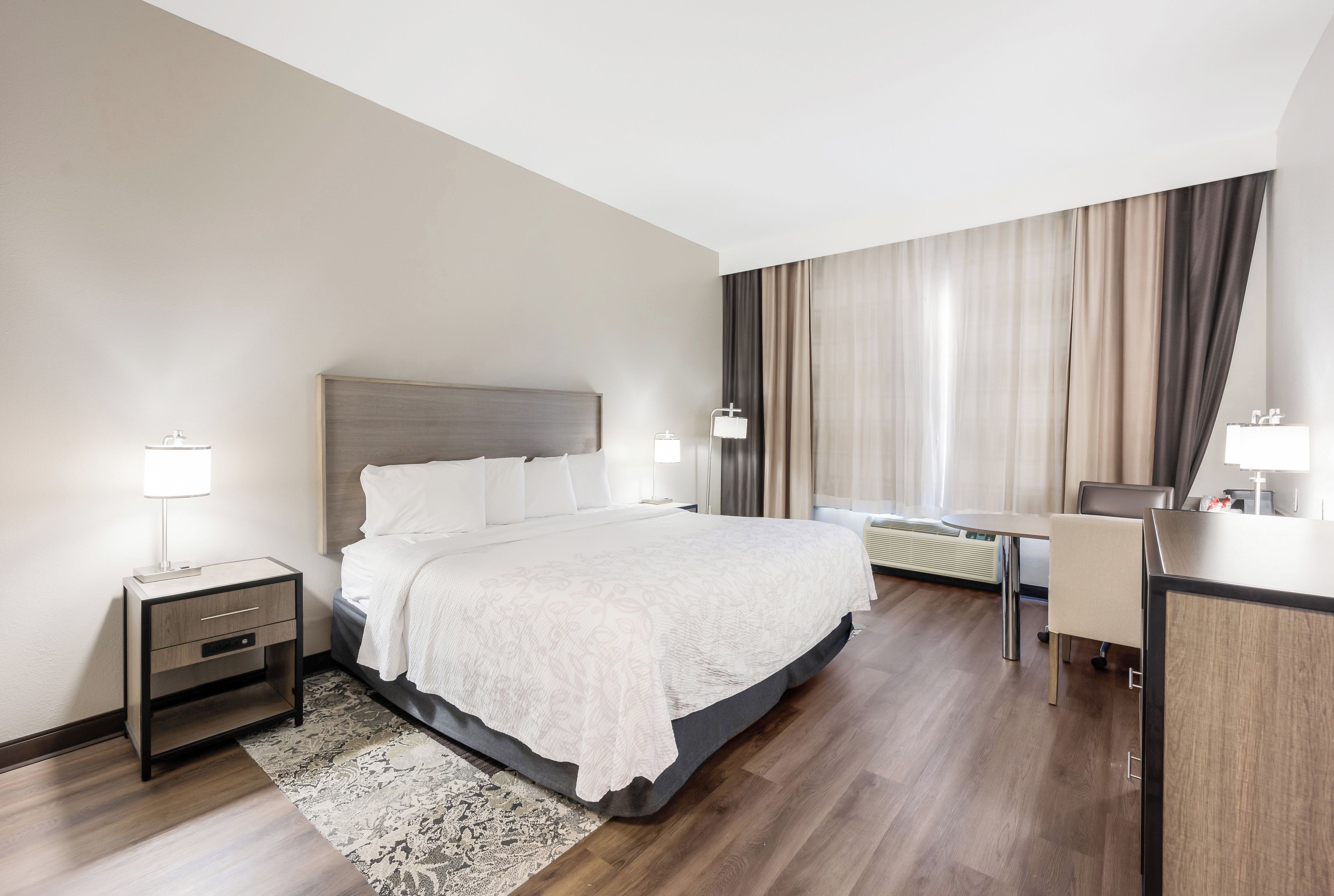 A hotel room with a large bed, bedside tables, a desk, and a chair.