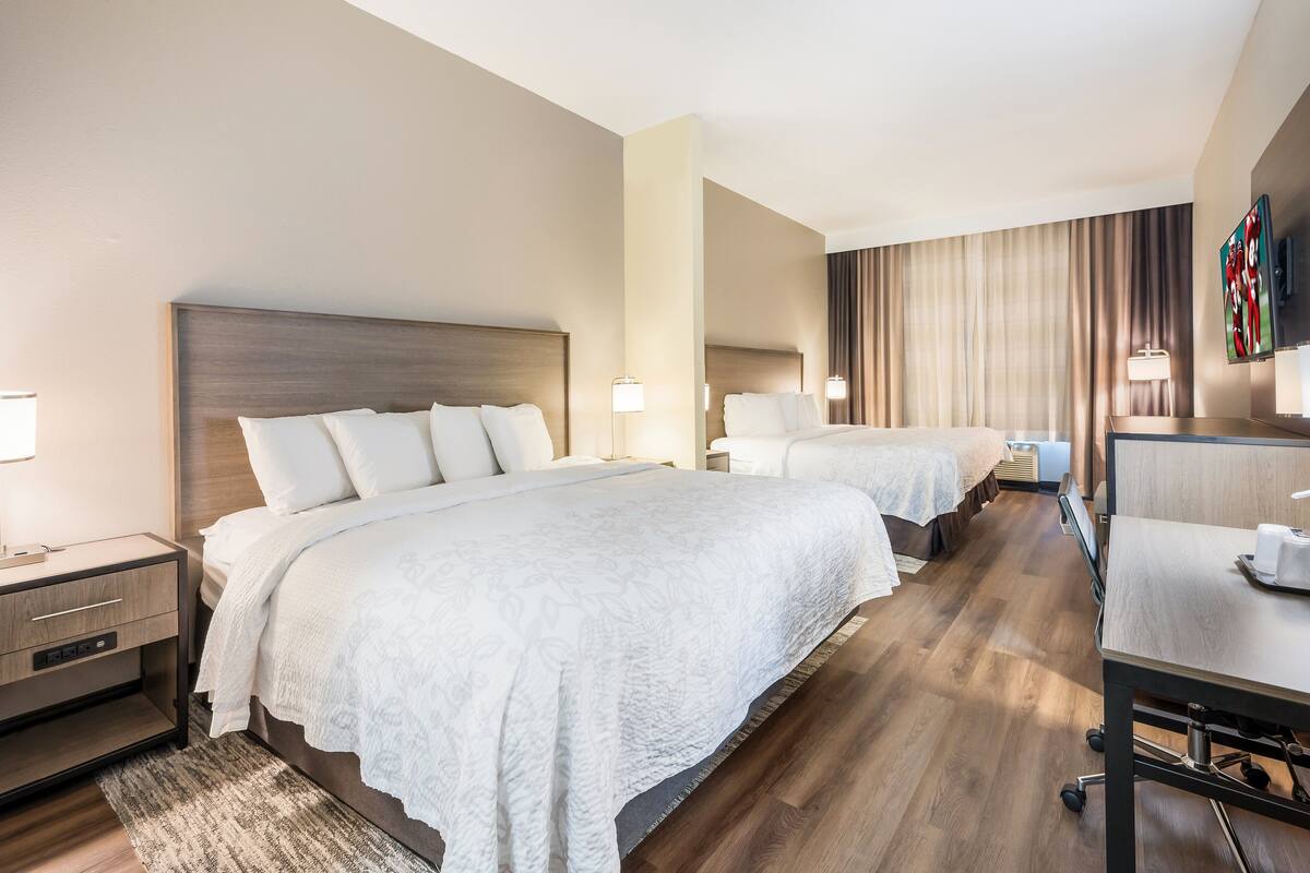 Una habitación de hotel con dos camas, un escritorio y un televisor.