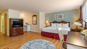 A hotel room with a bed, a desk, a television, a chair, and a round rug.
