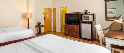 Habitación de hotel con dos camas, un escritorio, una silla, un televisor, un microondas y un aparador.