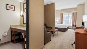 Een hotelkamer met een badkamer, een bed, een bureau en een stoel.