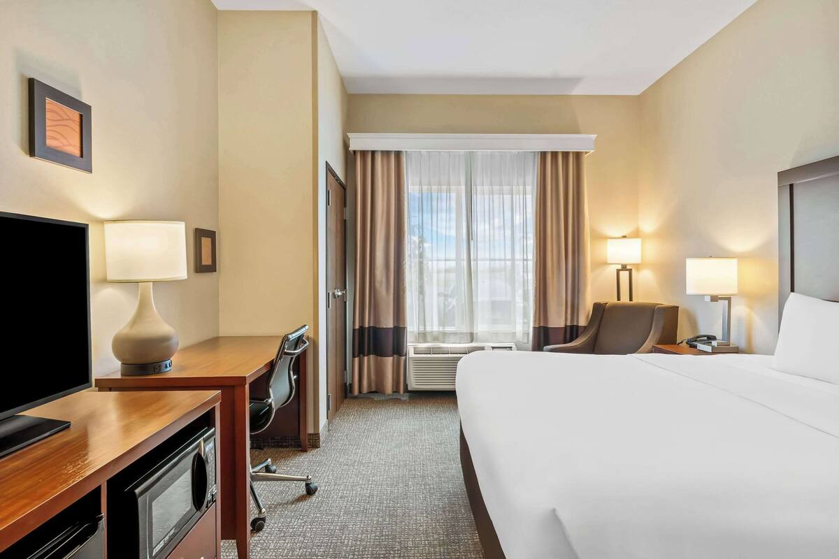 A hotel room with a bed, desk, TV, and two lamps.