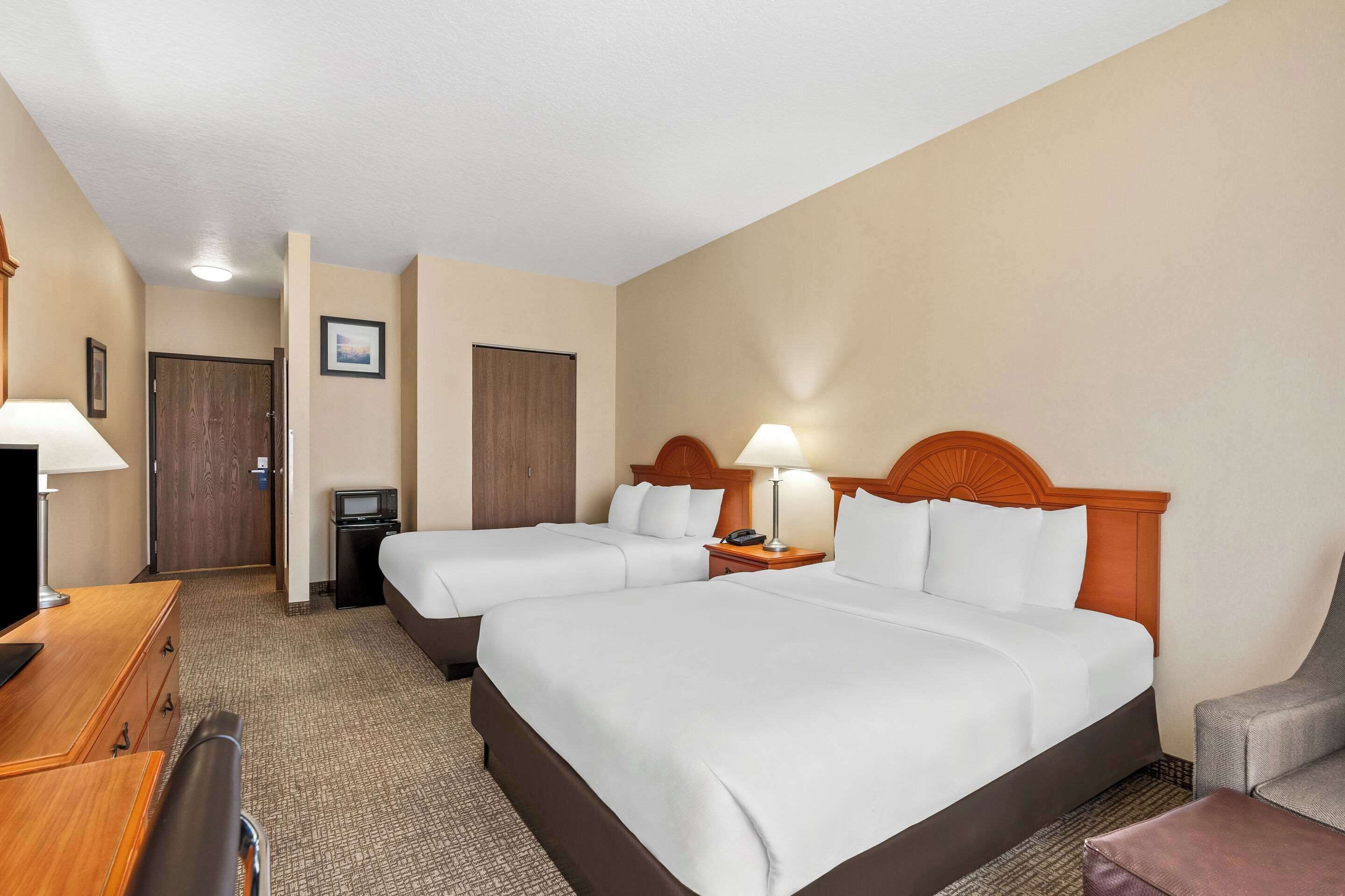 Habitación de hotel con dos camas, un escritorio, una silla y un televisor.