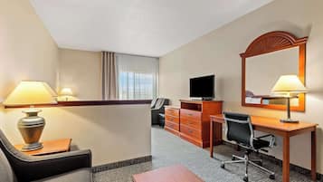Una habitación de hotel con escritorio, silla, televisión y un espejo grande.