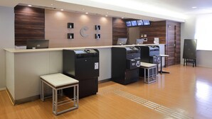 Un espace d’accueil comprenant un comptoir, des ordinateurs et un grand écran.