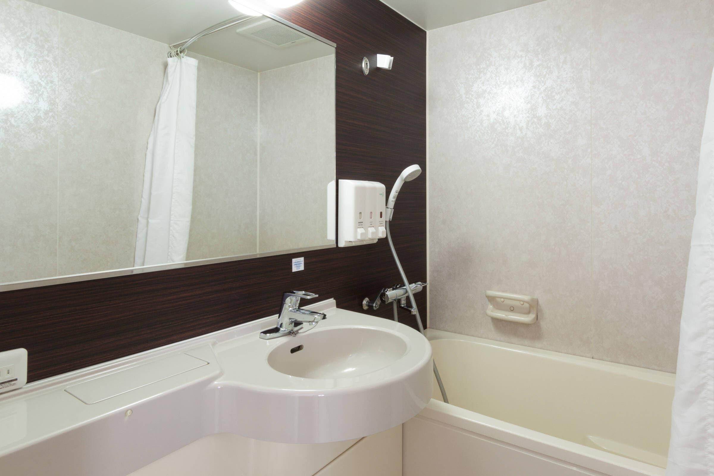 A bathroom with a white sink, a mirror, a shower, and a bathtub.