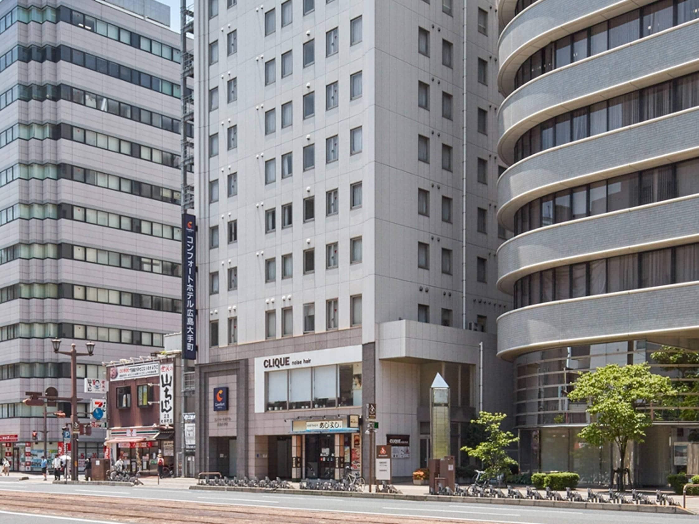 A multi-story hotel with a modern design, featuring a prominent entrance with a glass facade and signage for a hair salon.