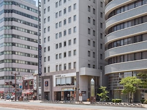 Um hotel com vários andares, design moderno, com entrada destacada e fachada de vidro, e placa indicando um salão de beleza.